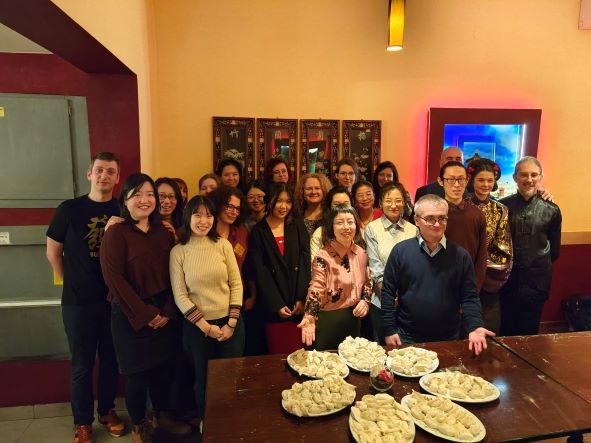Grupa pracowników i współpracowników Instytutu Konfucjusza, w chińskiej restauracji, z talerzami świeżo ulepionych chińskich pierogów