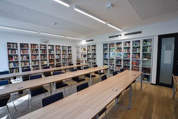 Zdjęcie biblioteki, kilka ławek, przy ścianach regały z książkami